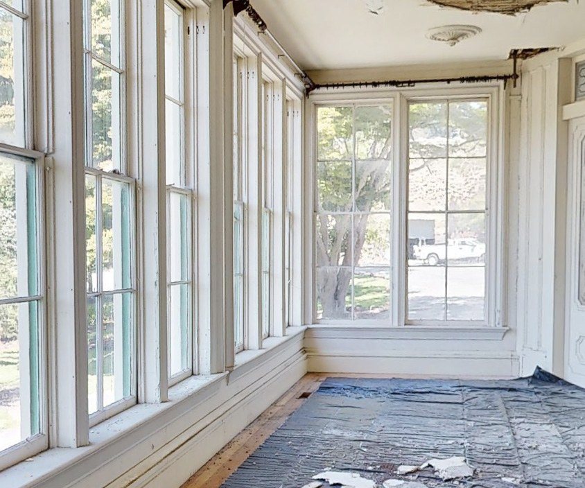 The glass sun porch today, with damaged flooring and peeling finishes